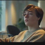 a fit young adult, exhibiting symptoms of vitamin deficiencies such as fatigue and pale skin, is seated in a modern, minimalistic office space, illuminated by soft, even lighting that highlights their concerned expression against a clean, uncluttered background.